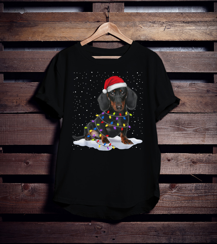 Dachshund Santa Hat Wrapped In Christmas Tree Lights In Snow With Falling Snowflakes T-Shirt