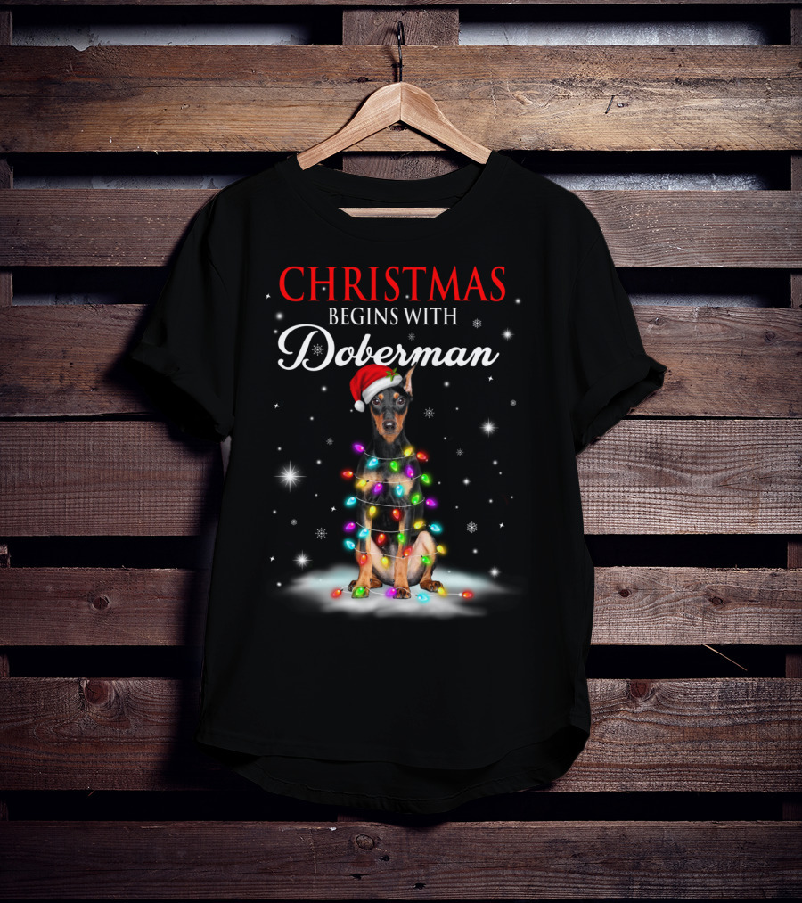Christmas Begins With Doberman Wrapped In Holiday Lights And Santa Hat Snowflakes T-Shirt