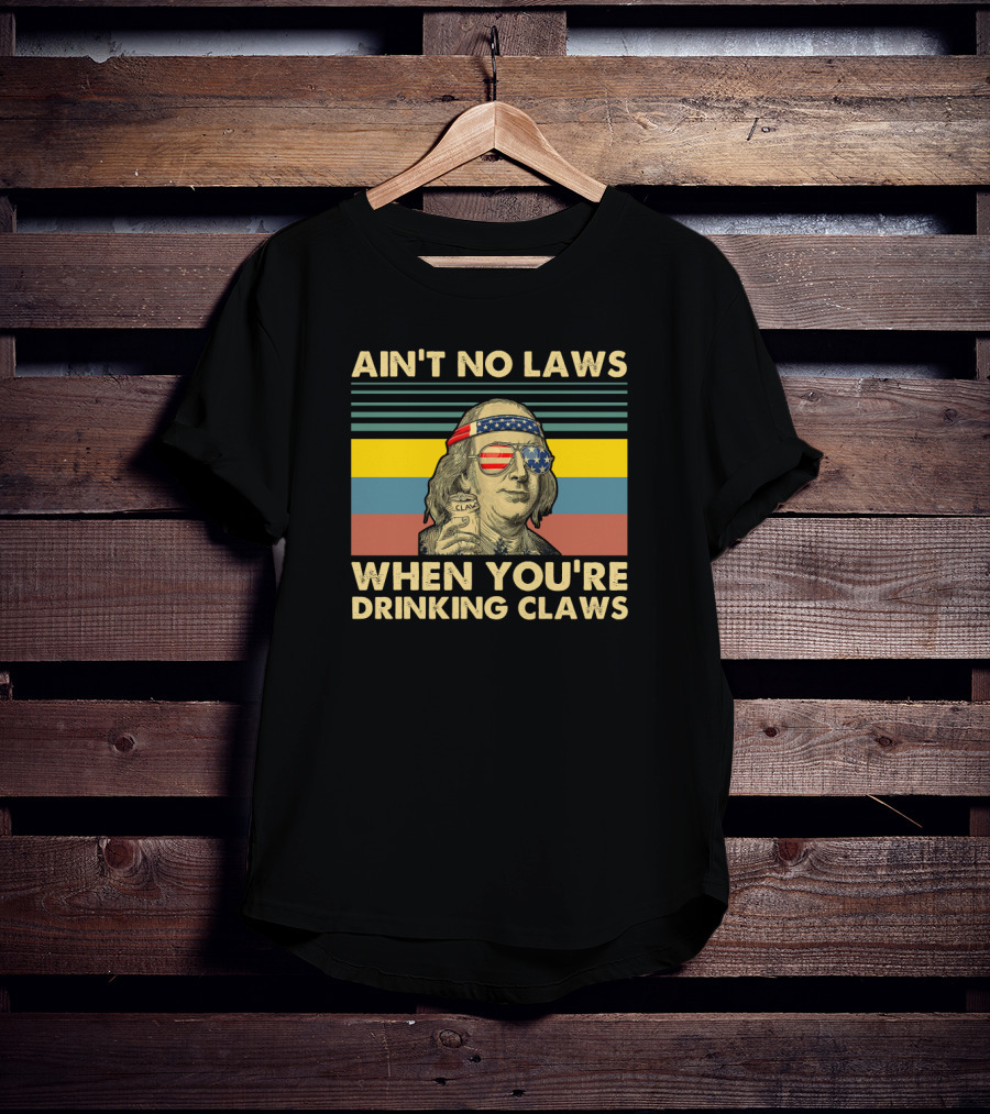 Ain't No Laws When You're Drinking Claws Vintage Benjamin Franklin With American Flag Glasses And Headband Can Of Clarified Beverage Stripes Background T-Shirt