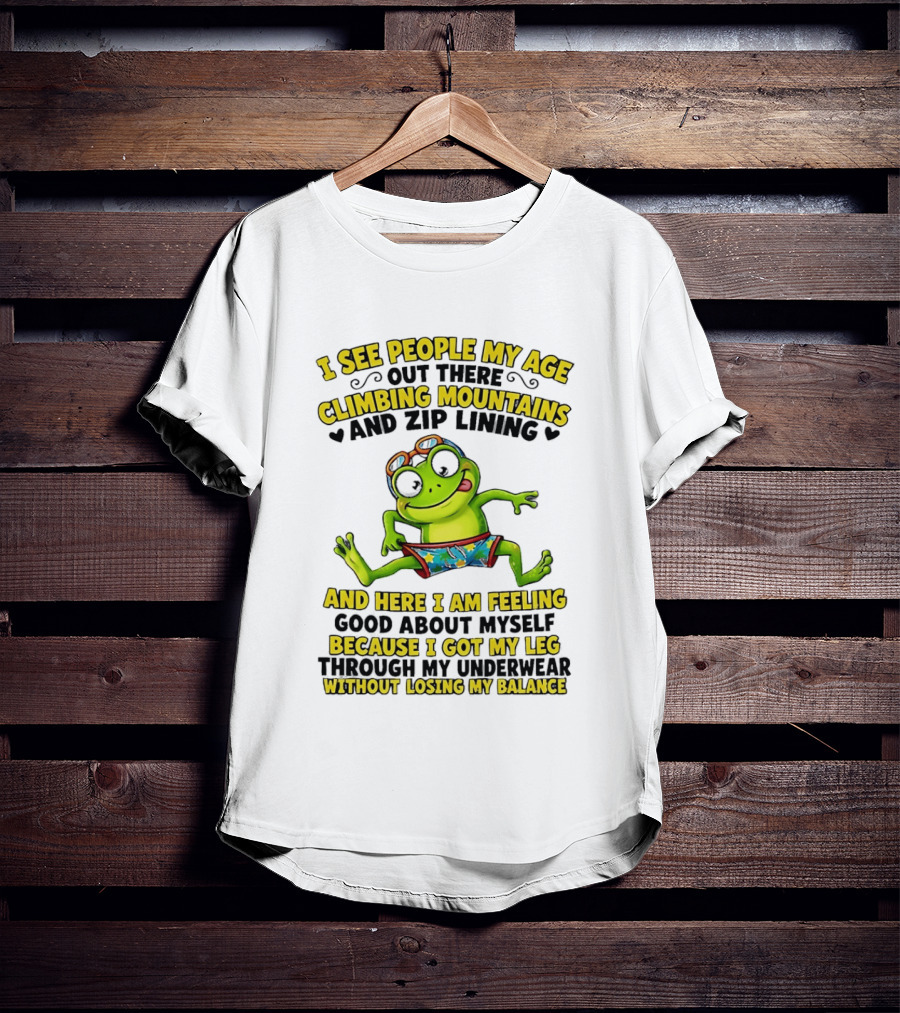I See People My Age Climbing Mountains And Zip Lining Cartoon Frog Feeling Good Without Losing Balance T-Shirt